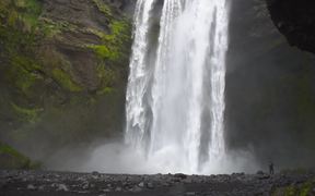 Man At the Base of Large Waterfall