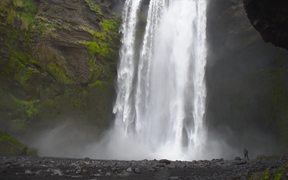 Man At the Base of Large Waterfall