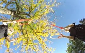 Duo Juggles Rings and Square Frames Beneath Tree